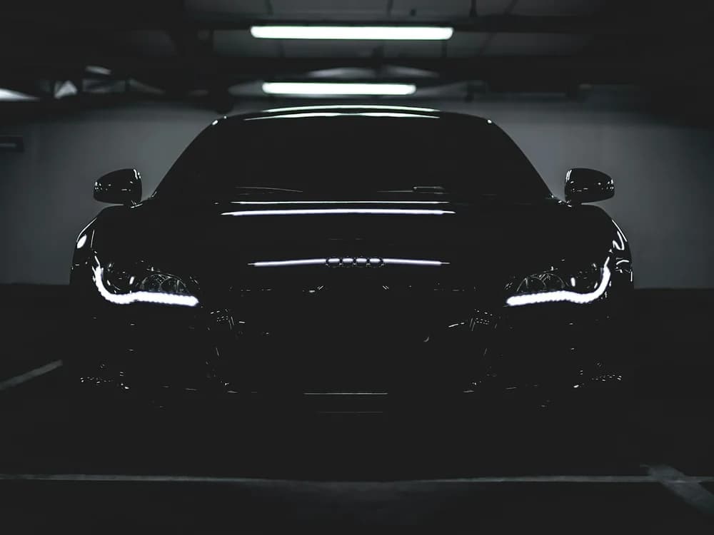 A standard black car parked in a dark garage