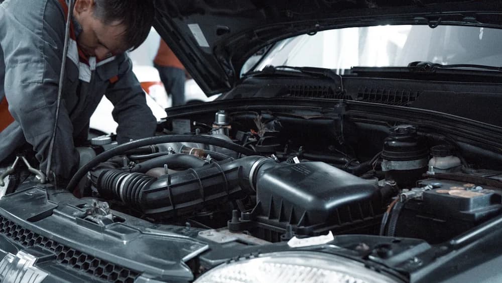 A technician working under the bonnet of a car